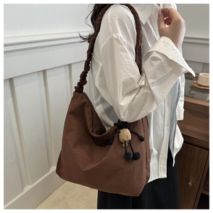 Detail of hobo tote bag with ruched handle, dark brown canvas, and sheep plush charm