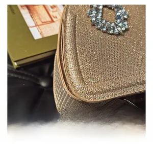 Gros plan d'un sac de soirée doré à paillettes avec boucle cristal et couture fine