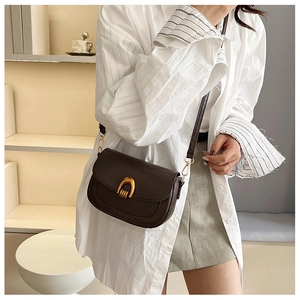 Brown retro saddle bag detail featuring a U-shaped gold metal buckle and matte leather