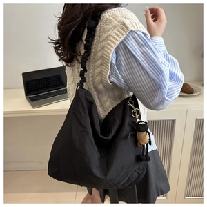 Detail of black nylon tote bag featuring a scrunchie shoulder strap and sheep charm