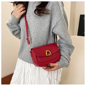 Detail of red saddle bag featuring unique gold metal buckle and smooth leather texture