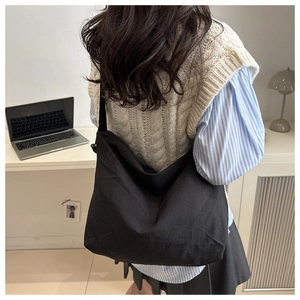 Detailed back view of a large black canvas tote bag for students on a model