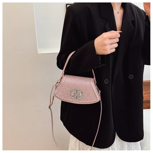 Détail d'un sac rose pailleté avec boucle ronde en strass et design élégant à rabat