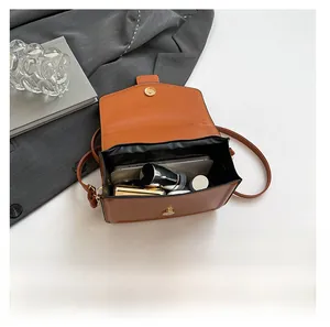 Detail view of the spacious interior of the caramel leather crossbody square bag