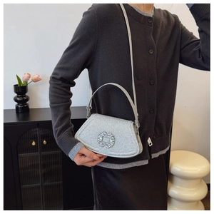 Détail du sac à bandoulière argenté brillant avec boucle florale en cristal étincelant