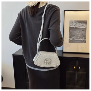 Silver glitter shoulder bag with sparkling rhinestone buckle worn by a female model