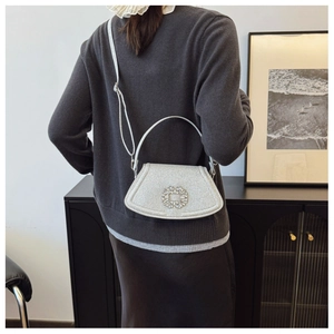 Détail du sac argenté scintillant avec une boucle ronde en cristal et une fine bandoulière