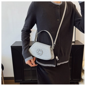 Close-up of a silver glitter mini handbag with a rhinestone buckle and slim shoulder strap