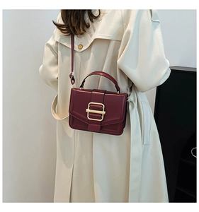 Deep red square handbag featuring a prominent gold metal buckle and elegant top handle