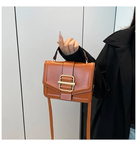 Detailed close-up of brown leather bag with elegant gold metal buckle and hand strap