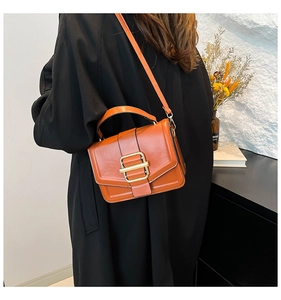 Classic orange square crossbody bag in glossy leather styled with a black coat