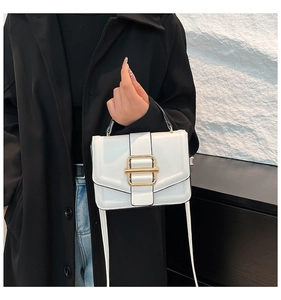 Close-up of white glossy patent leather handbag with a golden metallic clasp detail