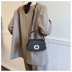 Détail d'un sac à main noir scintillant avec boucle carrée en cristal sur un blazer gris