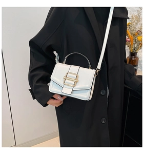 Close-up of white glossy PU leather handbag with a gold metal double buckle detail