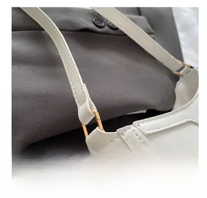 Detailed close-up of golden metal D-ring buckle and stitching on white leather bag