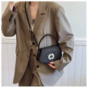 Detail of glittery black crossbody bag featuring a large crystal square buckle and strap