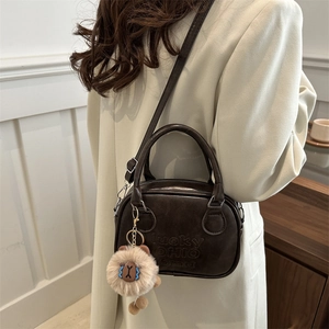 Brown vintage PU leather shoulder bag with plush charm and embossed logo detail