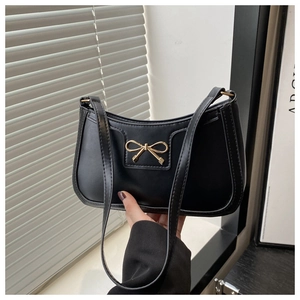Close-up of black PU leather crescent bag with a decorative gold bow metal buckle