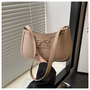 Detail of a beige PU leather shoulder bag featuring a decorative gold bow metal clasp