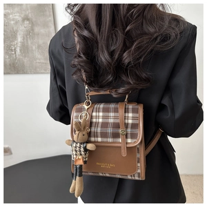 Detail of vintage plaid backpack with brown PU leather trim and a cute bunny pendant