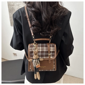 Back view of brown checkered vintage backpack with cute rabbit charm on black blazer