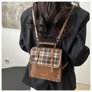 Detailed back view of a plaid and brown leather backpack worn by a model
