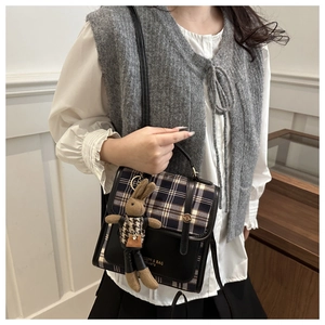 Detail of plaid patchwork handbag with vintage clasp and cute rabbit keychain accessory