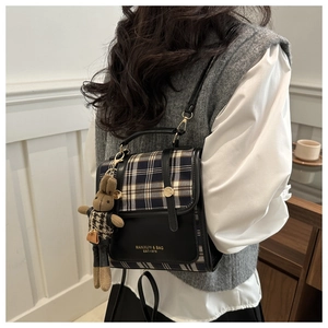 Close-up of contrast patchwork handbag with plaid detail and cute rabbit charm