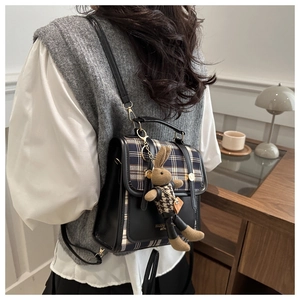 Detail of vintage plaid backpack with metal buckle and plush rabbit pendant accessory