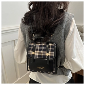 Nahaufnahme eines Vintage-Mini-Rucksacks mit Karomuster und Lederriemen am Model getragen