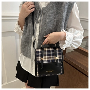 Close-up of vintage plaid crossbody bag with gold stud details and leather straps