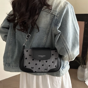 Sac bandoulière chic à pois avec finitions en cuir et broderies porté par un mannequin