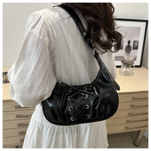 Detail of black bow hobo bag with lace-up drawstring and silver eyelets on the shoulder strap