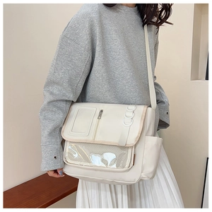 Mannequin portant un grand sac messager blanc crème avec détails de poche en filet transparent