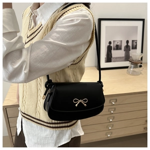 Détail du sac sous le bras en cuir noir avec une boucle nœud dorée au style vintage