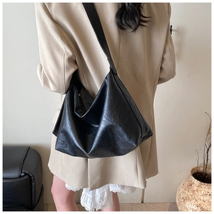 Detail of minimalist black oversized tote bag with soft leather texture and wide shoulder strap