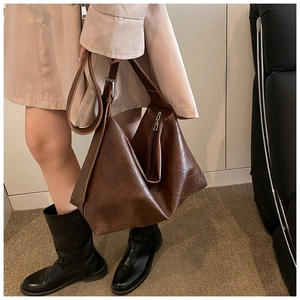 Detail of dark brown oil wax leather tote bag featuring adjustable strap and silver hardware