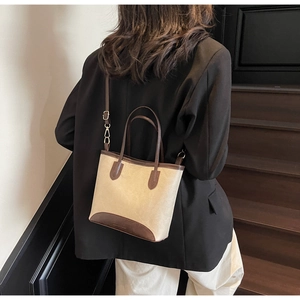 Detail of a vintage-style canvas tote bag with brown leather trim worn as a crossbody