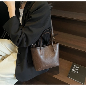Detail of dark brown leather bucket bag with embossed Fashion & Bags logo on the bottom