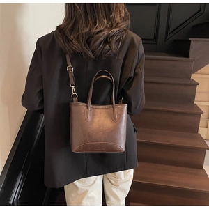 Detail of vintage brown leather bucket bag with top handles and adjustable shoulder strap