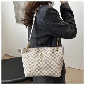 Detail of cream chain tote bag with all-over M pattern and golden deer charm