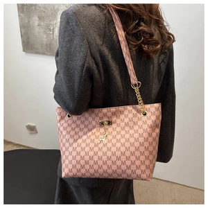 Detailed view of pink tote bag with M-letter print and golden deer charm on chain strap