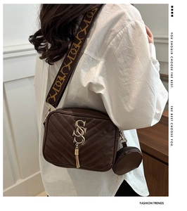 Detail of dark brown quilted camera bag with wide strap and mini round coin purse