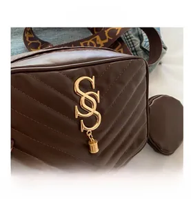 Detail of V-quilted dark brown crossbody bag with gold logo and patterned wide strap