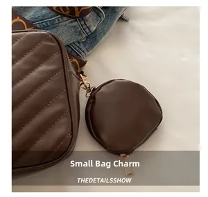 Detailed close-up of dark brown quilted leather mini bag charm with gold metal hardware