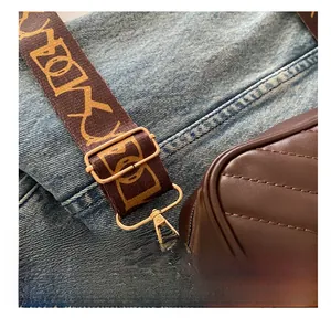Close-up of adjustable canvas strap with metal buckle on brown quilted crossbody bag