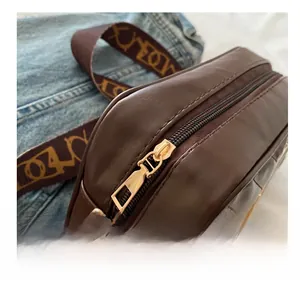Close-up of golden metal zipper and retro patterned wide strap on brown shoulder bag
