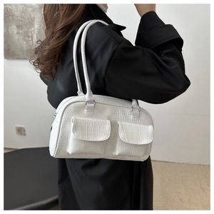 Close-up of white croc-embossed tote bag with dual front pockets on model's shoulder