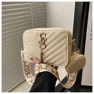 Detail of cream quilted crossbody bag with gold S-logo tassel and wide jacquard strap