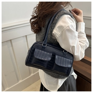 Detail of navy blue croc-effect tote bag with double flap pockets and top zipper closure